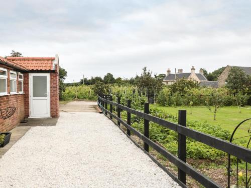 a driveway leading to a house with a fence at Bowler Yard Cottage in Sookholme