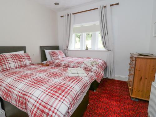 a bedroom with two beds and a window at Upper Highlees Farm in Luddenden Foot