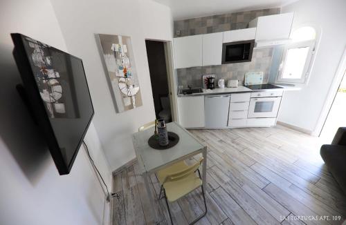 una cocina con armarios blancos y una mesa en una habitación en Triplex Bungalow Las Tortugas 109, en Arona