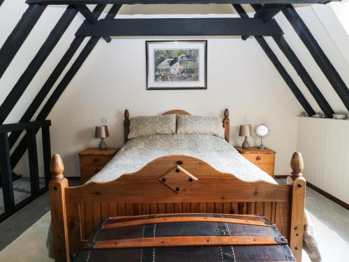 - une chambre mansardée avec un lit en bois dans l'établissement Mrs Dale's Cottage, à Clenchwarton