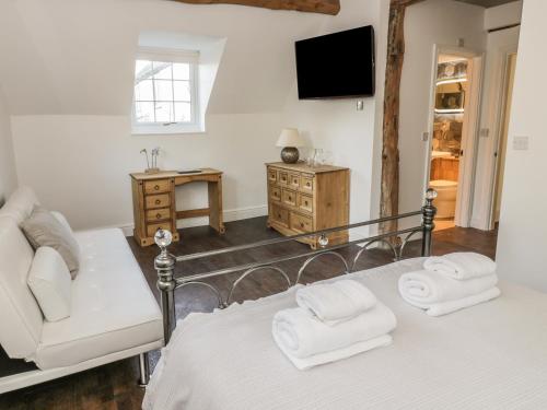 a bedroom with a bed and a couch and a tv at Lower Tundridge Cottage in Suckley