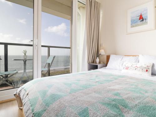 a bedroom with a bed and a view of the ocean at 12 West End Point in Pwllheli