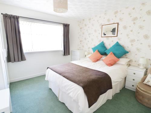 a bedroom with a large bed with blue and orange pillows at Trigfa Cottage in Abersoch
