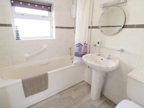 a white bathroom with a sink and a tub and a toilet at Trigfa Cottage in Abersoch