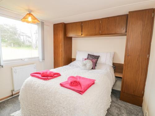 a bedroom with a bed with pink towels on it at Y Caban Clyd in Morfa Nefyn