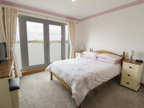 a bedroom with a bed and a large window at 2 Y Bae in Trearddur