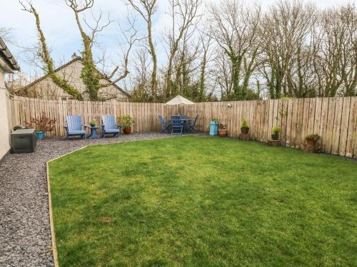 a backyard with a fence and a table and chairs at Hafod Wen in Pentraeth