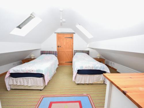 1 dormitorio en el ático con 2 camas y mesa en Beudy Mawr, en Llanddeiniolen