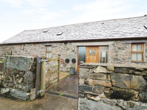 an old stone house with a gate and a stone wall at Beudy Mawr in Llanddeiniolen