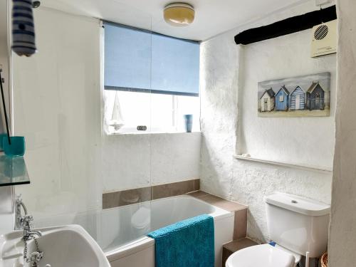 uma casa de banho com uma banheira, um WC e um lavatório. em Threshings Cottage em Tintagel