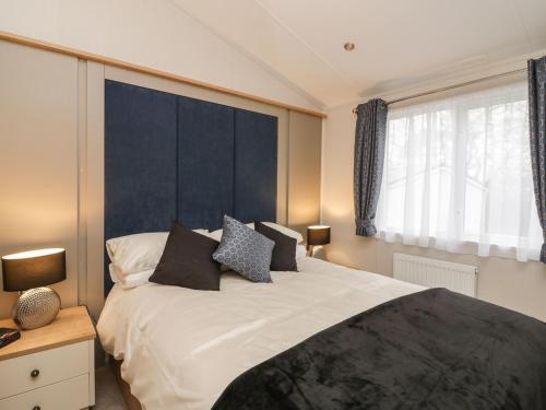 a bedroom with a large bed with a blue headboard at Woodstock Lodge in Skelmorlie