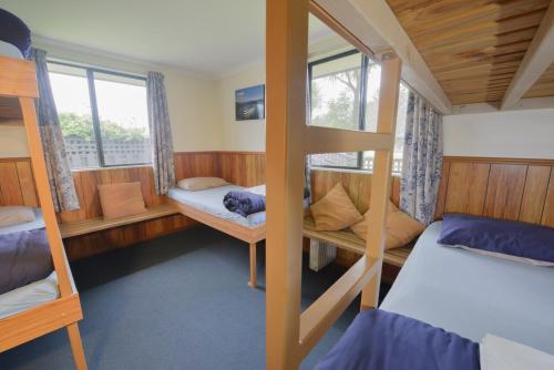 a room with three bunk beds and a window at Wilderness Backpackers in Haast