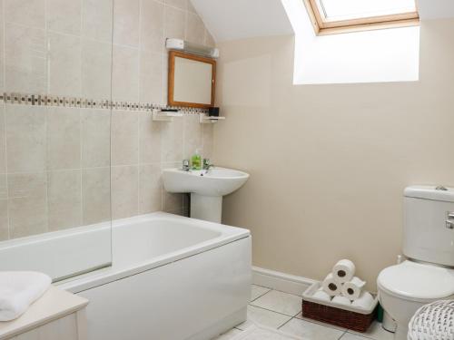 a bathroom with a white tub and a sink at Ryelands Cottage in Easthope