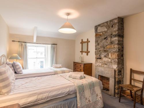 a bedroom with two beds and a stone fireplace at Fisherman's Cottage in Seahouses
