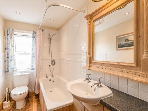 a bathroom with a sink and a tub and a toilet at Fisherman's Cottage in Seahouses