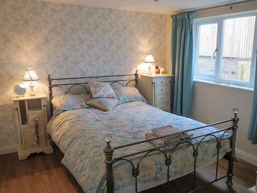 a bedroom with a bed and two lamps and a window at The Old Corn Store in Keighley