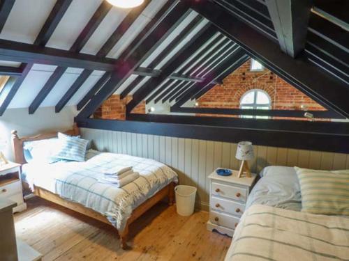 a attic bedroom with two beds and a dresser and a window at The Old School in Panton