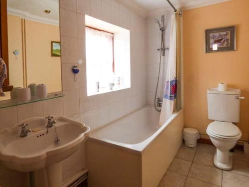 a bathroom with a tub and a toilet and a sink at Kingsley Cottage in Hickling