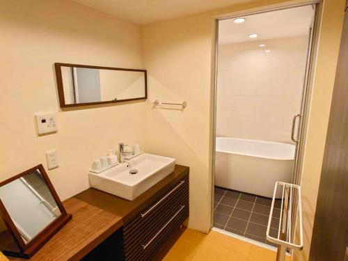 Un baño con lavabo blanco y ducha. en Nijo Yurakuan, en Kioto