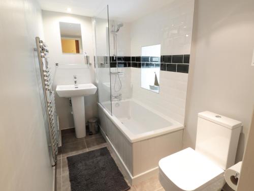 La salle de bains est pourvue d'une baignoire, d'un lavabo et de toilettes. dans l'établissement Holly Cottage, à Matlock
