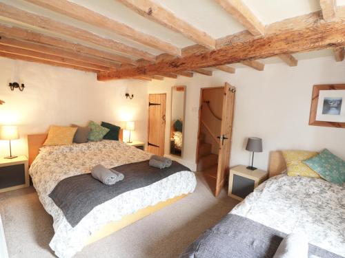 two beds in a room with wooden ceilings at Holly Cottage in Matlock