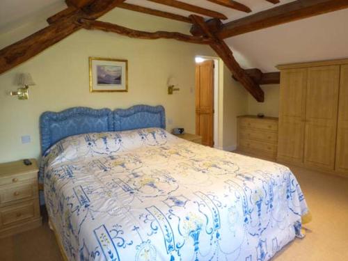 a bedroom with a bed with a blue and white bedspread at Pheasant Cottage in Grange Over Sands