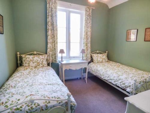 a bedroom with two beds and a desk and a window at The Gate House in Oakamoor