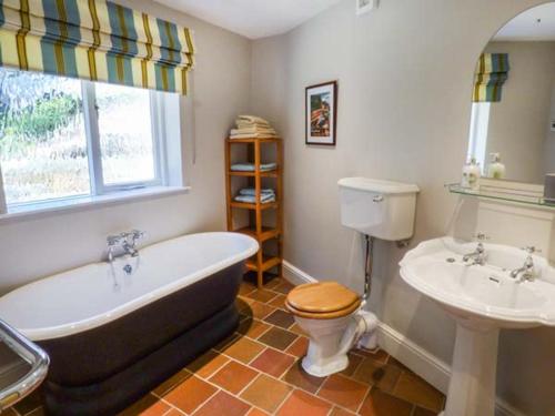 a bathroom with a tub and a toilet and a sink at The Gate House in Oakamoor