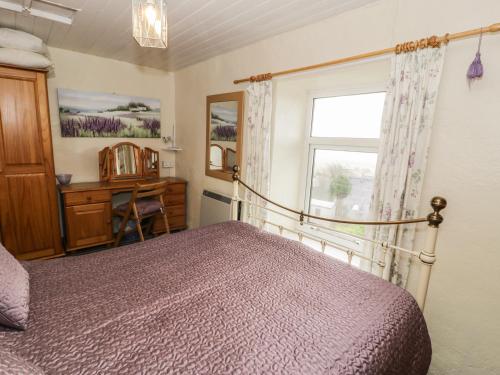 a bedroom with a bed and a window and a desk at Merlin in Pwllheli