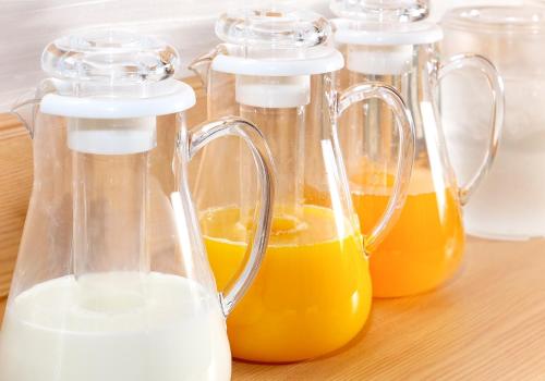 four glass containers of orange juice on a wooden table at Daiwa Roynet Hotel Yamagata Ekimae in Yamagata