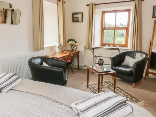 West BurtonにあるBarn Cottageのベッドルーム1室(ベッド1台、椅子2脚、デスク付)