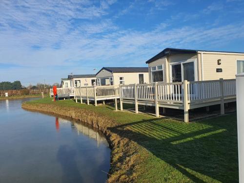 a row of mobile homes next to a river at Cosy caravans Meadow lake Golden Palm Resort in Chapel Saint Leonards