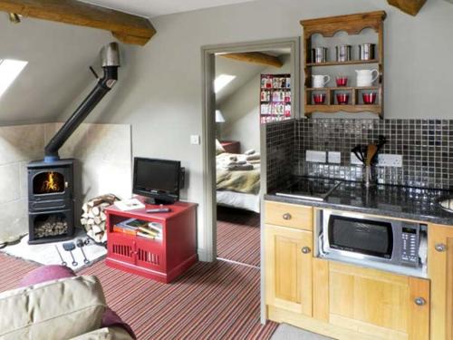 a room with a kitchen with a stove and a living room at The Hayloft in Lastingham