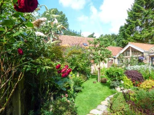 a garden with red roses and a house at The Hayloft in Lastingham