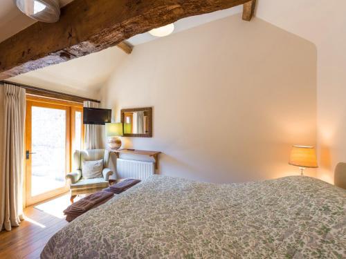 a bedroom with a bed and a chair and a window at The Byre in Highley