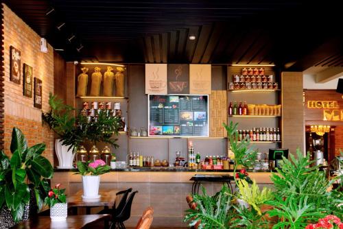 a bar in a restaurant with tables and plants at Mekong Gia Lai Hotel - Me Kong Pleiku in Pleiku