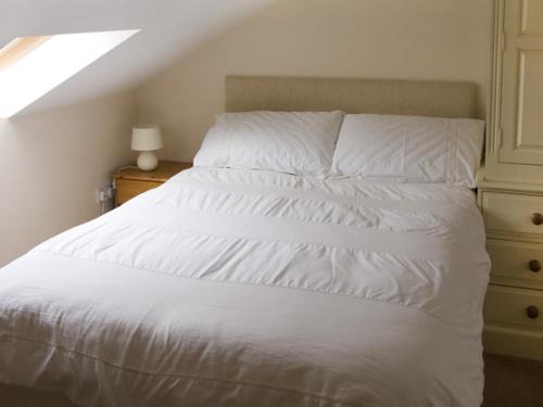 a bedroom with a white bed and a dresser at The Loft in Annan