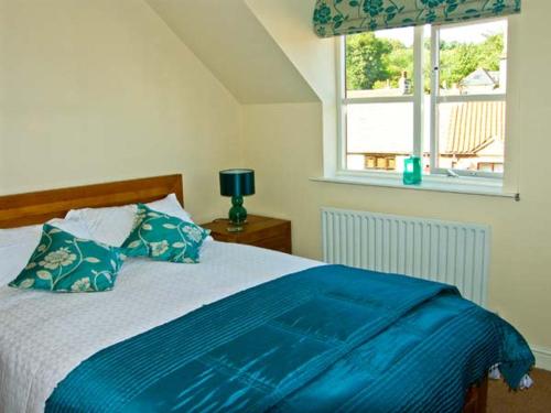 Un dormitorio con una cama con sábanas azules y una ventana. en Water's Edge, en Whitby
