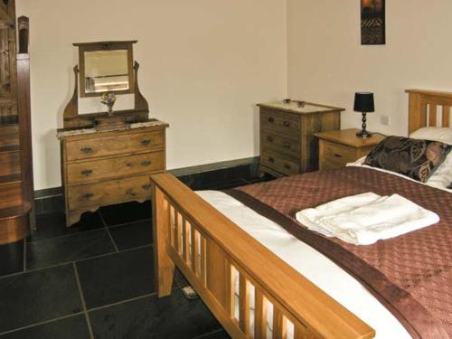 a bedroom with a bed and a dresser and a mirror at The Byre in Abergavenny
