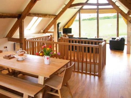 a dining room with a wooden table and a living room at Shepherd's Hut in Blandford Forum