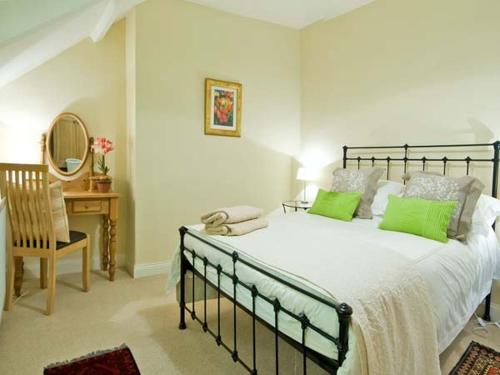 a bedroom with a large bed with green pillows at The Old Farmhouse in Bowsden