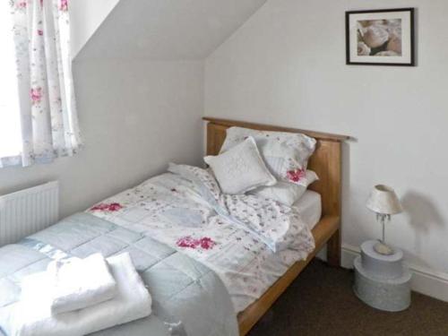 a bedroom with a bed with white sheets and pillows at Grove Cottage in Malton