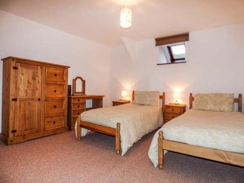 a bedroom with two beds and a dresser at Y Bwthyn in Llanbedr