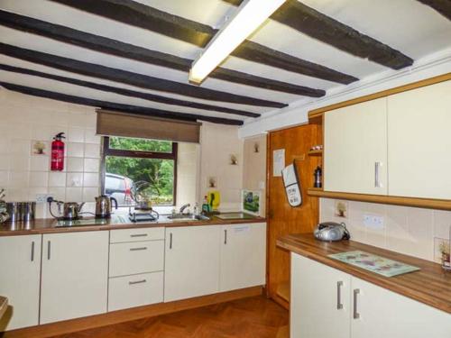 a kitchen with white cabinets and a black and white ceiling at Y Bwthyn in Llanbedr