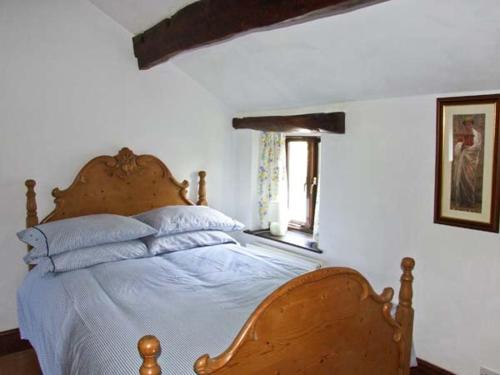 a bedroom with a bed with a wooden headboard and a window at The Cottage in Buxton