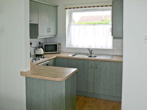 a kitchen with blue cabinets and a sink and a window at Seascape in Lowestoft