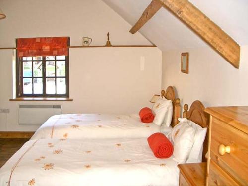 a bedroom with a bed with red pillows on it at Tailor's Cottage in Abbey-Cwmhir