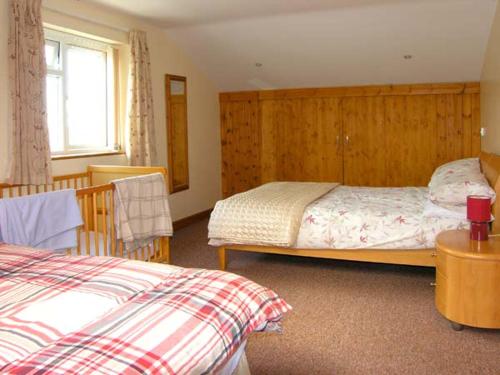 a bedroom with two beds and a window at Farmhouse Cottage in Pentraeth