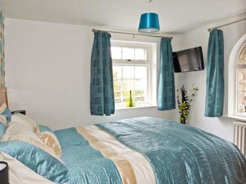 a bedroom with a bed with blue curtains and a window at The Old Mill in Grange Over Sands