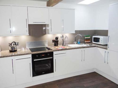 a kitchen with white cabinets and a black appliance at Curlew Cottage in Barnard Castle